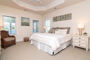 A bedroom with a large bed, two bedside tables, a chair, and a ceiling fan. - Waterfront Resort | Community Amenities | Sleeps 13 (Selbyville)