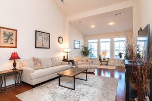 A spacious living room with a large window, a sofa, a coffee table, and a fireplace. - Waterfront Resort | Community Amenities | Sleeps 13 (Selbyville)