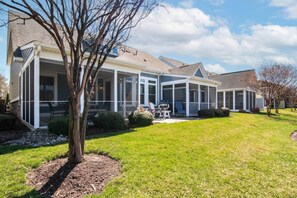 A residential property with a covered patio, a lawn, and a tree. - Waterfront Resort | Community Amenities | Sleeps 13 (Selbyville)