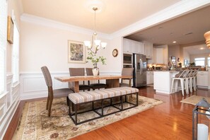 A dining area with a wooden table, cushioned chairs, a bench, and a chandelier. - Waterfront Resort | Community Amenities | Sleeps 13 (Selbyville)