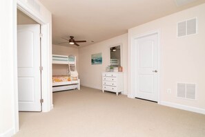 A bedroom with a bunk bed, a dresser, a ceiling fan, and a door. - Waterfront Resort | Community Amenities | Sleeps 13 (Selbyville)