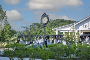 A clock with 'Bay-Side' written on it, a covered seating area, and a building labeled 'The Over Inn' in the background. - Waterfront Resort | Community Amenities | Sleeps 13 (Selbyville)