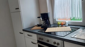 Een keuken met een koffiezetapparaat, een snijplank en een notitieboekje op het aanrecht.
