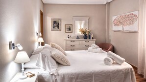 Una camera da letto con un letto grande, un comodino con una lampada, un comò e uno specchio.