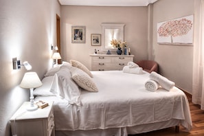 A bedroom with a large bed, a nightstand with a lamp, a dresser, and a mirror. - Torrevieja 2 BR and Parking (Torrevieja)