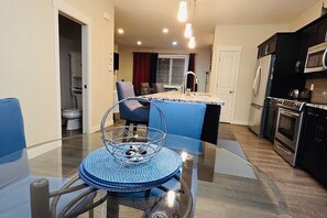 Una cocina moderna con comedor, que incluye una mesa de vidrio, sillas azules y una isla de cocina.
