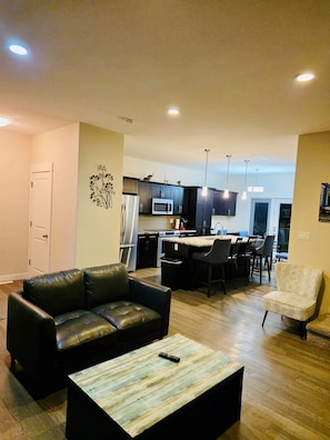 A modern living room with a leather sofa, a coffee table, and a dining area with chairs.
