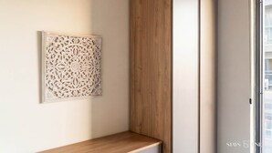 A modern room with a wooden cabinet, a decorative wall panel, and a window. - 6th Floor Mercury Suite Apartment with Pool Access (Saint Julian's)