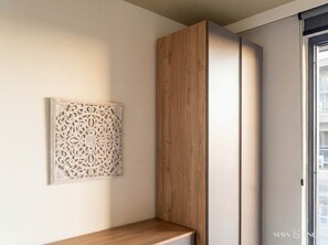 Une pièce moderne avec un meuble en bois, un panneau décoratif au mur et une fenêtre.