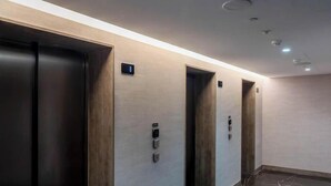 A hallway with three elevators, each with a control panel and a small sign above the door. - 6th Floor Mercury Suite Apartment with Pool Access (Saint Julian's)