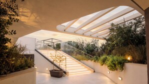 A modern interior with a glass staircase, a flat ceiling, and a view of greenery outside. - 6th Floor Mercury Suite Apartment with Pool Access (Saint Julian's)
