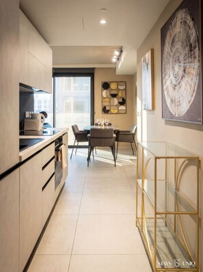 Une cuisine moderne avec un coin repas, une grande fenêtre et une œuvre d’art contemporaine.