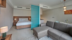 Et moderne hotelværelse med en seng, en sofa, et lille bord og et tv ophængt på væggen.