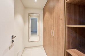 Un pasillo con un armario de madera, un espejo y una puerta que da a otra habitación.