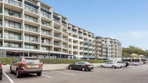 A multi-story hotel with balconies, a parking lot, and a clear sky. - Coastal Breeze Nelson Bay: King Bed, Spa bath, Private balcony, Resort pool (Nelson Bay)
