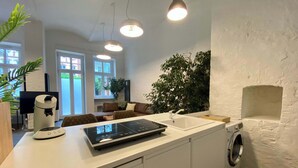 Eine moderne Küche mit einer integrierten Waschmaschine, einer Arbeitsplatte mit Kaffeemaschine und einem großen Fenster.