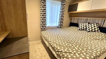 A bedroom with a bed, a wardrobe, and a window with curtains.