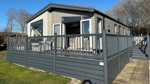 En moderne mobilbolig med en overdækket veranda, store vinduer og en grå facade.