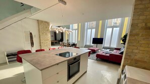 A modern kitchen with a central island, red chairs, a dining area, and a living space with a red sofa. - Design Loft with Pool Table for 6 (Berlin)