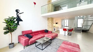 A modern living room with a red sofa, a coffee table, and a potted plant. - Design Loft with Pool Table for 6 (Berlin)