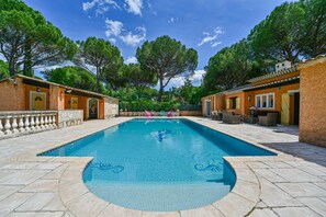 A rectangular swimming pool with clear blue water, surrounded by stone tiles and two-story buildings with yellow doors. - Les Terrasses – Villa with Private Pool in a Peaceful Setting (Vidauban)