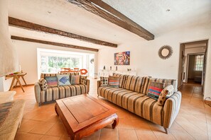 Uma sala de estar com sofás listrados, uma mesa de centro de madeira e um quadro na parede.