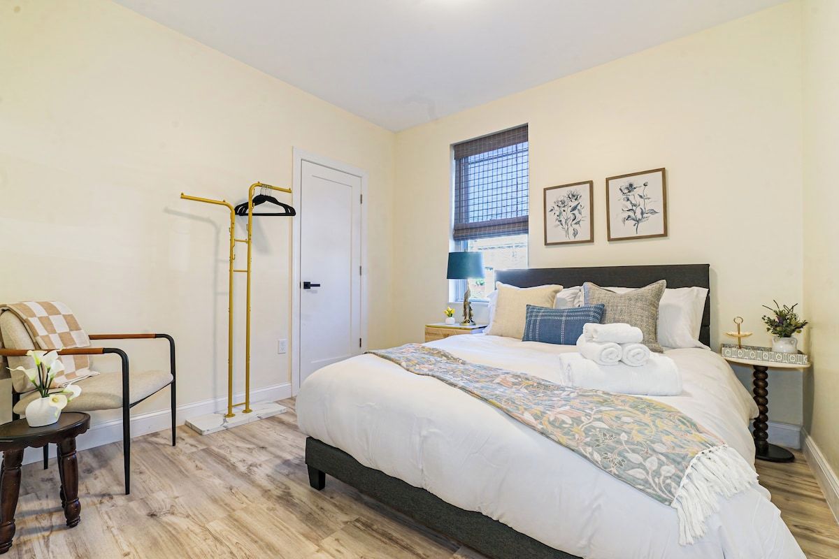 A bedroom with a bed, a chair, a window, and a door.