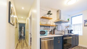 Cocina moderna con lavavajillas, horno y microondas. Hay repisas de madera sobre la encimera y una ventana con cortinas.