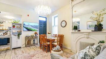 A well-lit living room with a dining area, a television, and a fireplace.