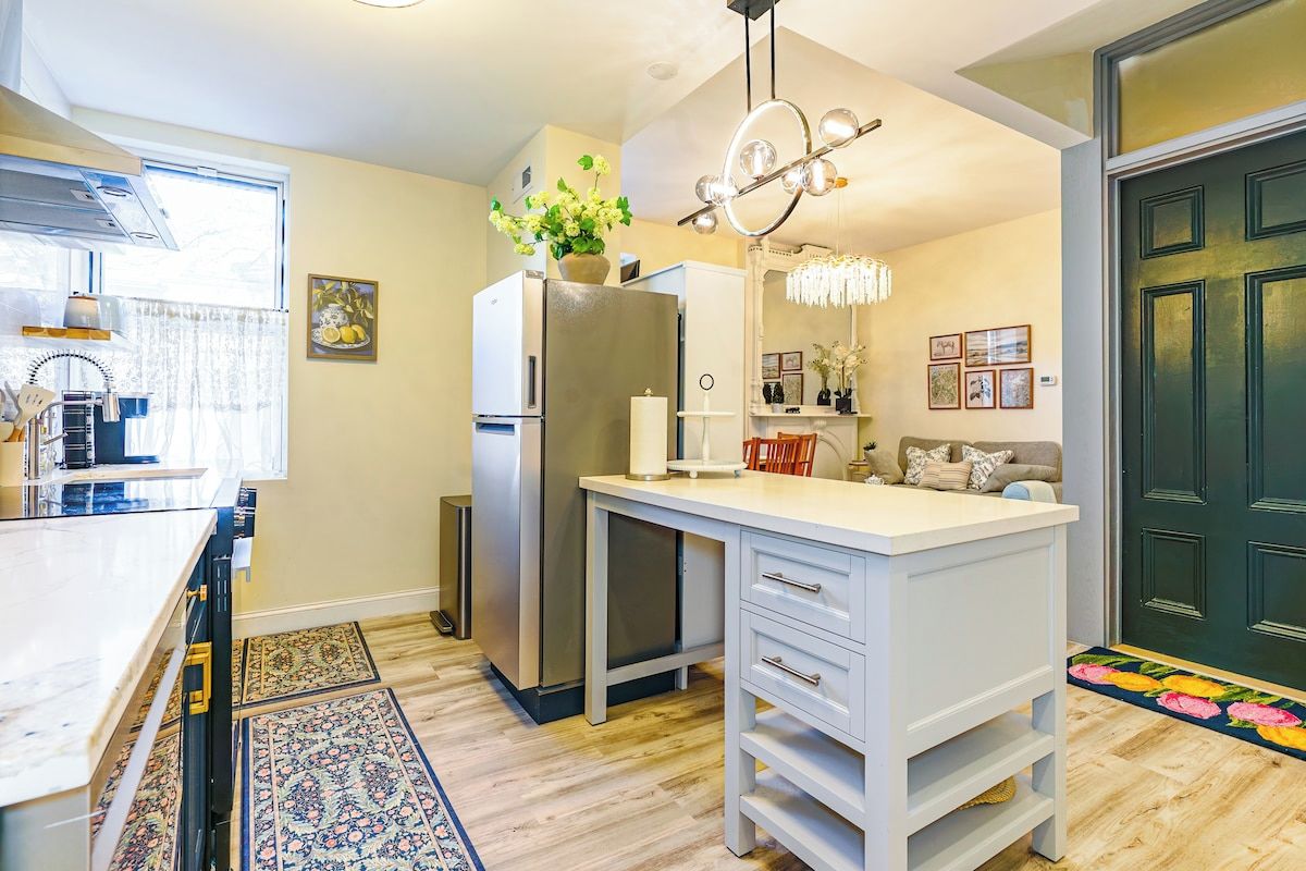 A modern kitchen with a central island, stainless steel appliances, and a chandelier.