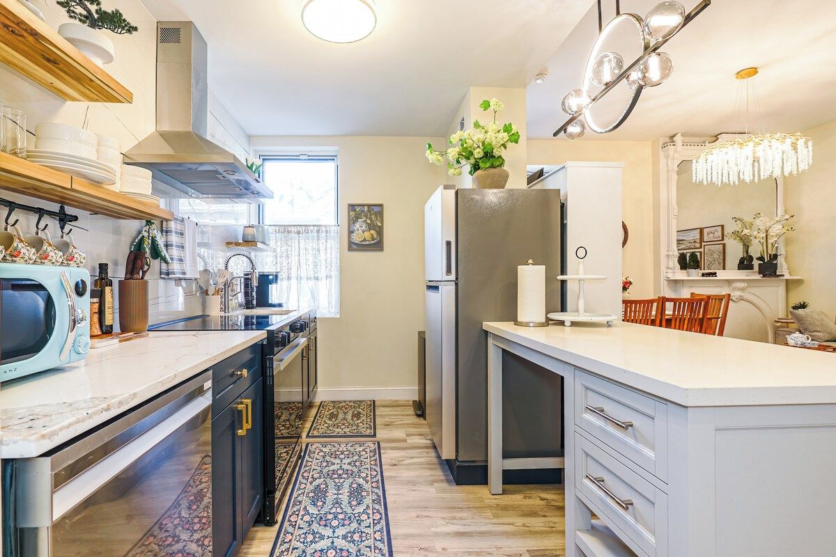 A modern kitchen with a central island, built-in appliances, and a decorative chandelier.