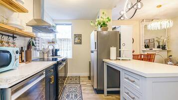 A modern kitchen with a central island, built-in appliances, and a decorative chandelier.