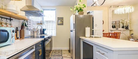 A modern kitchen with a central island, built-in appliances, and a decorative chandelier.