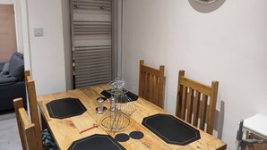 En matplats med ett träbord, stolar, ett metallställ, en klocka och ett element.