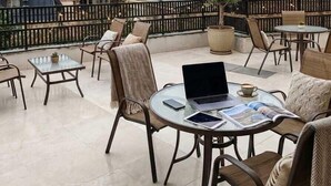A rooftop terrace with outdoor seating, a laptop, and a view of the cityscape and mountains. - Tutto Passa Hotel (Tbilisi)