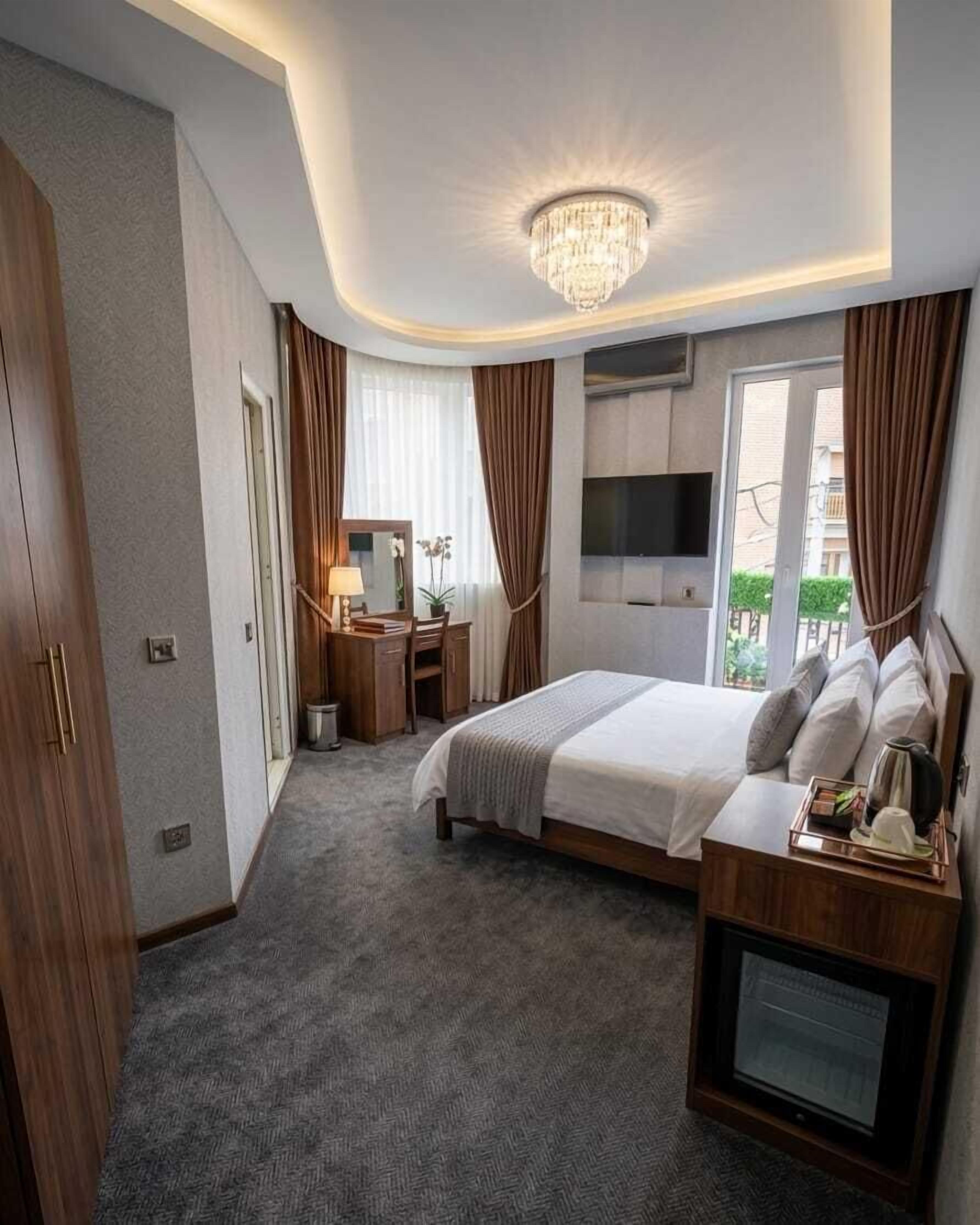 Een moderne hotelkamer met een groot bed, een bureau met stoel, een televisie en een kroonluchter.