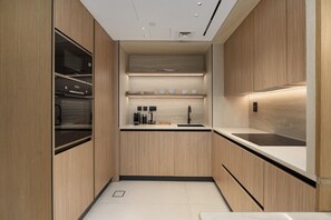 A modern kitchen with wooden cabinetry, a built-in oven, a sink, and a countertop. - Prime JLT Stay | Near Metro & Lakeside Dining (Dubai)