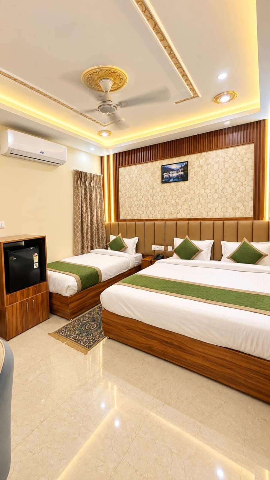 A hotel room with two beds, a television, an air conditioning unit, and a decorative wall.