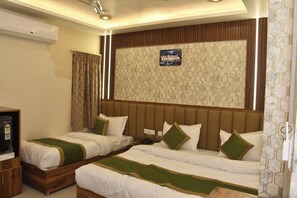 A hotel room with two beds, a wooden cabinet, an air conditioning unit, and a decorative wall panel. - BKRS Hotel (Varanasi)
