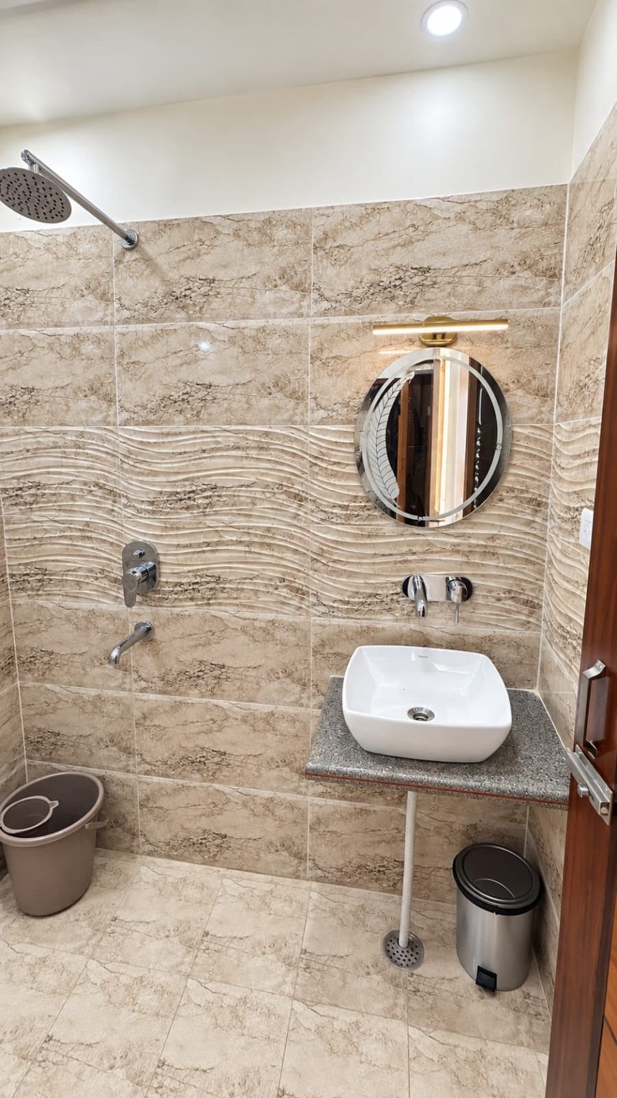 Un baño con ducha, lavamanos, inodoro y un cubo de basura.