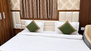 Una habitación de hotel con una cama grande, cabecera con diseño estampado y colcha verde acolchada.