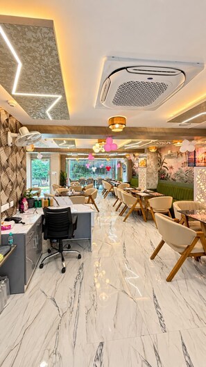 A modern interior with a marble floor, a reception desk, and a dining area with chairs and tables. - BKRS Hotel (Varanasi)