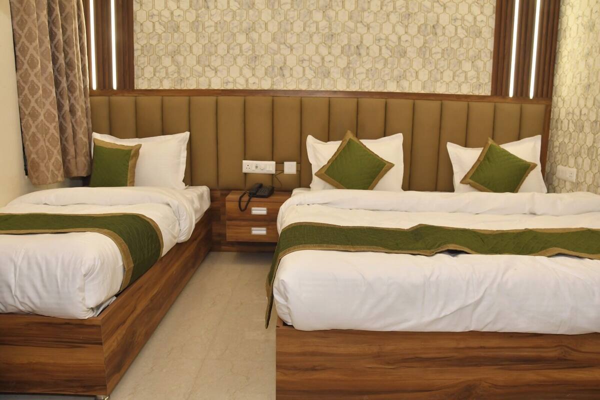 Habitación doble con dos camas, cabecero de madera, mesita de noche con teléfono y pared con diseño.