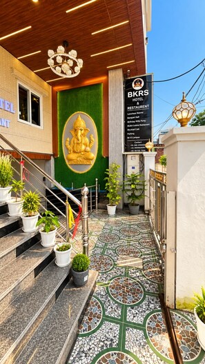 A hotel entrance with a staircase, potted plants, and a mosaic floor. - BKRS Hotel (Varanasi)