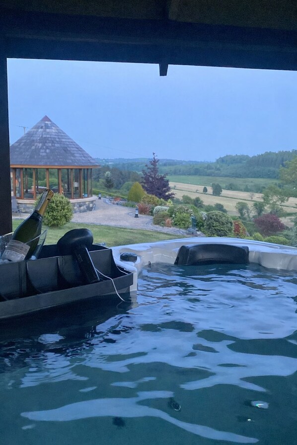 A hot tub with a view of a gazebo and a landscaped garden.