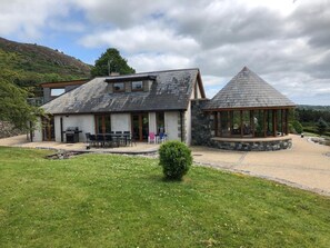 A building with a stone facade, a covered outdoor seating area, and a grassy yard. - 6 Bedroom Luxury Retreat Near Newcastle & Mourne Mountains | Hot Tub | Sleeps 15 (Castlewellan)