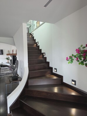 A modern staircase with a curved landing, dark wood steps, and wall-mounted lighting.