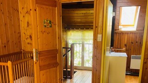 Ein Holzblockhaus mit Bett, Badezimmer und Balkon.