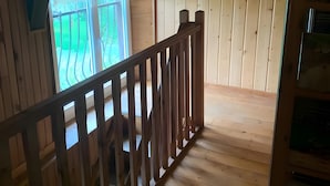 Un intérieur en bois avec un balcon, un tableau encadré au mur et une rambarde en bois.