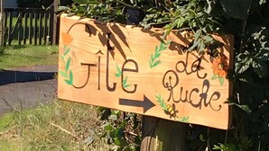 Ein hölzernes Hinweisschild mit dem Schriftzug 'Jete de Ruche' und einem nach rechts zeigenden Pfeil.